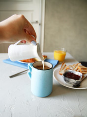 breakfast. hand. side view. light background. scrambled eggs, orange juice, toast, jam, croissants, coffee, milk, morning, close up