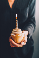 woman holding a birthday cupcake with candle