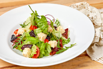 vegetarian salad with dried tomatoes and croutons on the wooden background