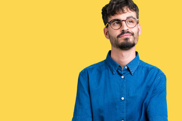Young handsome man wearing glasses over isolated background smiling looking side and staring away thinking.