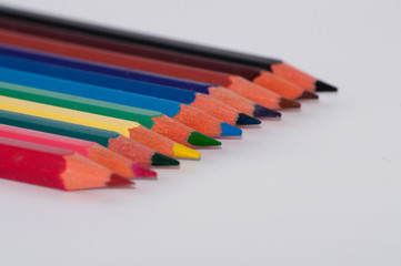 Many colored pencils on a white background close-up, macro, side view, with space for text.