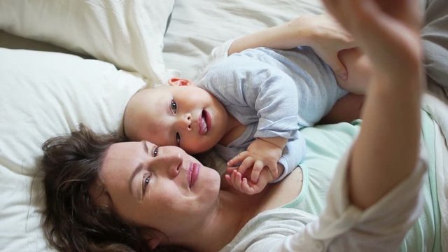 Self mom and baby in bed in the early morning. Concept of happy motherhood, mother's day
