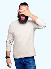 Young blond man wearing casual sweater smiling and laughing with hand on face covering eyes for surprise. Blind concept.