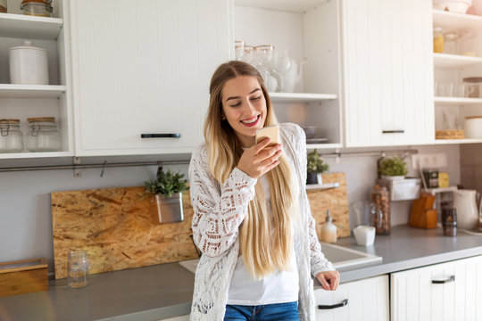 Young woman using her smartphone at home - Powered by Adobe