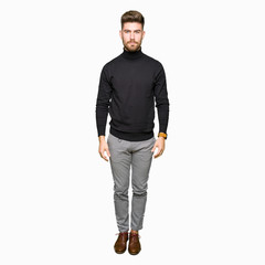 Young handsome blond man wearing winter sweater with serious expression on face. Simple and natural looking at the camera.