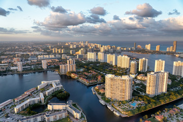 Fototapeta na wymiar Aerial view of Miami Beach at sunset from helicopter. City skyline and water. Cloudy skies, a vacation dream