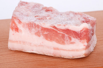 large piece of frozen pork belly on a cutting board