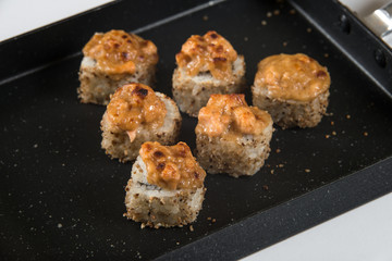 Japanese sushi rolls on a black frying pan. close view