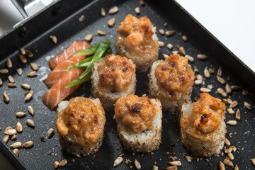 Japanese sushi rolls on a black frying pan. close view