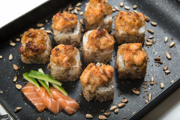Japanese sushi rolls on a black frying pan. close view