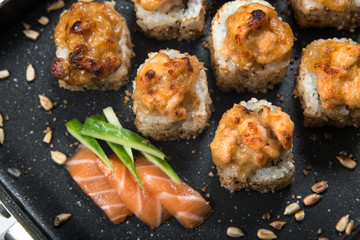 Japanese sushi rolls on a black frying pan. close view