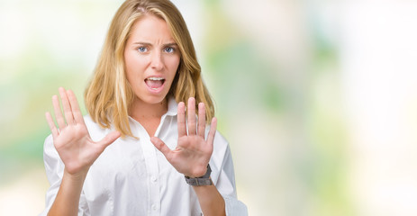 Beautiful young business woman over isolated background afraid and terrified with fear expression stop gesture with hands, shouting in shock. Panic concept.