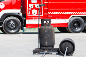 Naklejka na ściany i meble Gas tanks for fire fighting training with a fire truck background. 