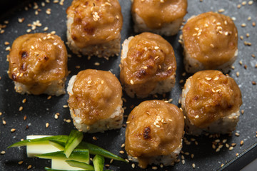 Japanese sushi rolls on a black frying pan. close view