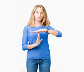 Beautiful young woman wearing blue sweater over isolated background Doing time out gesture with...