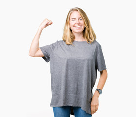 Fototapeta premium Beautiful young woman wearing oversize casual t-shirt over isolated background Strong person showing arm muscle, confident and proud of power