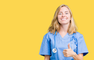 Beautiful young doctor woman wearing medical uniform over isolated background doing happy thumbs up...