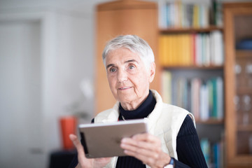 Fototapeta na wymiar Ältere Frau zu Hause aktiv mit Tablet