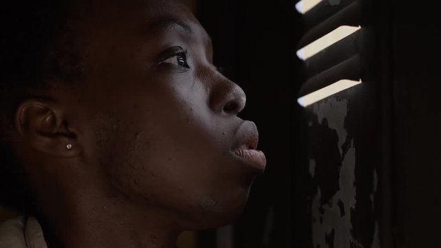 scared lonely young black woman hides behind the shutters.Violence against women