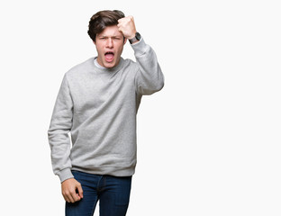 Fototapeta premium Young handsome sporty man wearing sweatshirt over isolated background angry and mad raising fist frustrated and furious while shouting with anger. Rage and aggressive concept.