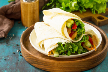 Healthy lunch snack. Tortilla wraps with grilled chicken and fresh vegetables on blue table. Chicken Tortilla, mexican street fast food. Copy space.