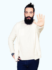 Young man with long hair and beard wearing sporty sweatshirt doing stop sing with palm of the hand. Warning expression with negative and serious gesture on the face.