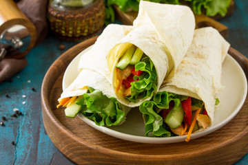 Healthy lunch snack. Tortilla wraps with grilled chicken and  fresh vegetables on blue table. Chicken Tortilla, mexican street fast food.