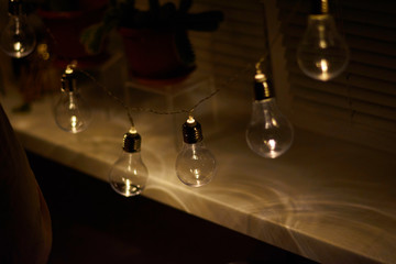 Garland of vintage bulb lamps with modern yellow LED lighting elements, close up photo