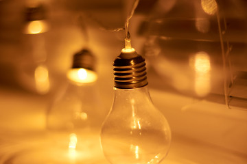 Garland of vintage bulb lamps with modern yellow LED lighting elements, close up photo
