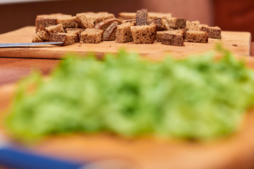 Whole grain bread put on kitchen wood plate with a chef holding gold knife for cut.