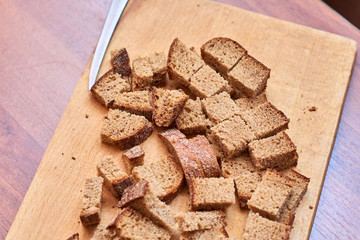 Whole grain bread put on kitchen wood plate with a chef holding gold knife for cut.