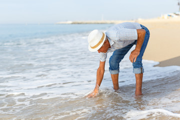 Elderly glad man checks the water temperature