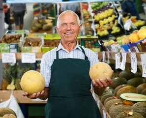 Elderly salesman working in greengrocery