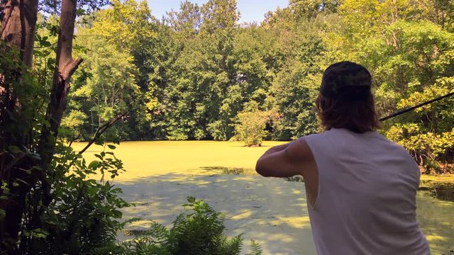 Man Fishing in a pond with algae