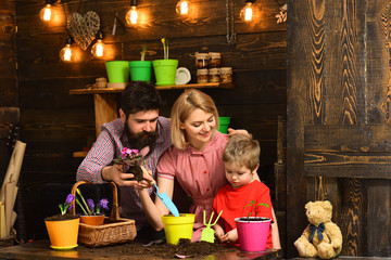 happy gardeners with spring flowers. Family day. Greenhouse. Flower care watering. Soil...