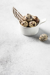 Close up quail eggs with bird feather in the white ceramic bowl on the white background