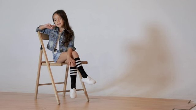 Cute little girl posing in photo studio. Children's photo session on a white background. kid sitting on a chair