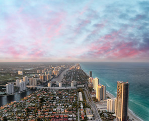 Aerial view of Miami Beach at sunset from helicopter. City skyline and water. Cloudy skies, a...