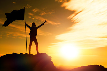 girl with a flag on top of the mountain against the evening sky. the achievement of the objectives, tourism, travel.