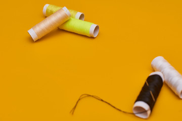 coils of thread with needles on yellow background