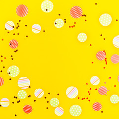 Festive confetti, ribbons and glitter on a bright yellow background. Birthday and summer holiday concept. Top view, flat lay, copy space