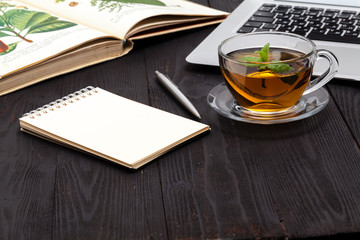 Desk with laptop, eyeglasses and a cup of tea on a wooden table