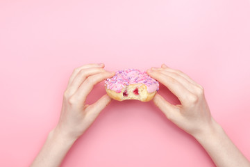 girl holding a glazed pink donut on a pink monochromatic background