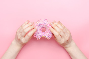 girl holding a glazed pink donut on a pink monochromatic background