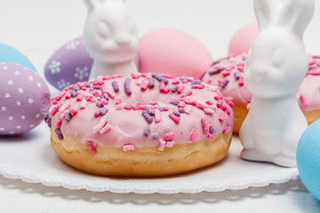 Easter bunnies and eggs on the table with donuts