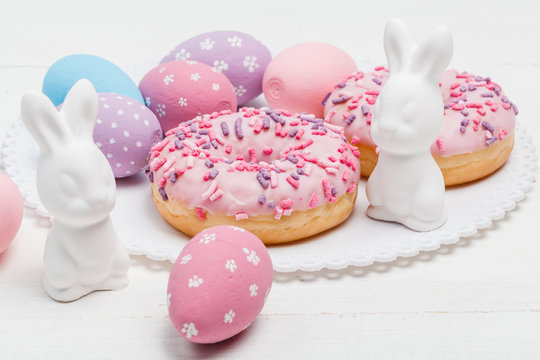 Easter bunnies and eggs on the table with donuts