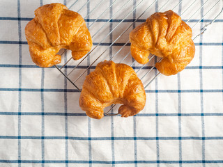 Top view of fresh croissants on checkered towel.