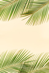 Fototapeta na wymiar Tropical green palm leaves on yellow background. Flat lay, top view