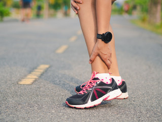 Athlete woman has ankle injury, sprained leg during running training. sport concept.