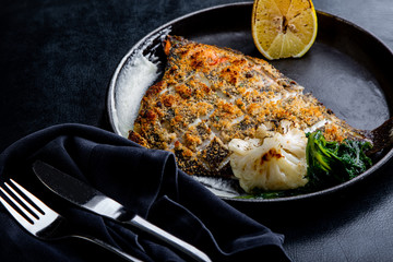 Flounder fillet roasted in a skillet with herbs and lemon